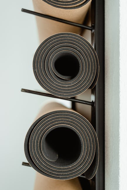 Rolled yoga mats neatly stacked on a rack indoors, ideal for fitness or wellness themes.